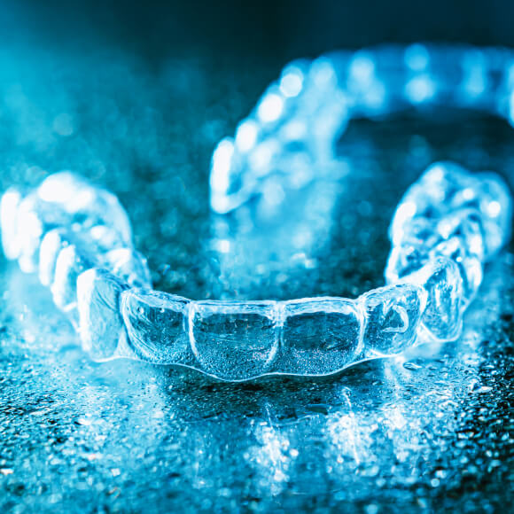 Pair of Invisalign trays on a reflective surface.