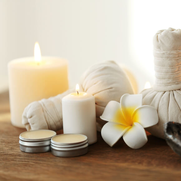 Arrangement of lit candles with a flower and cloth bundles.